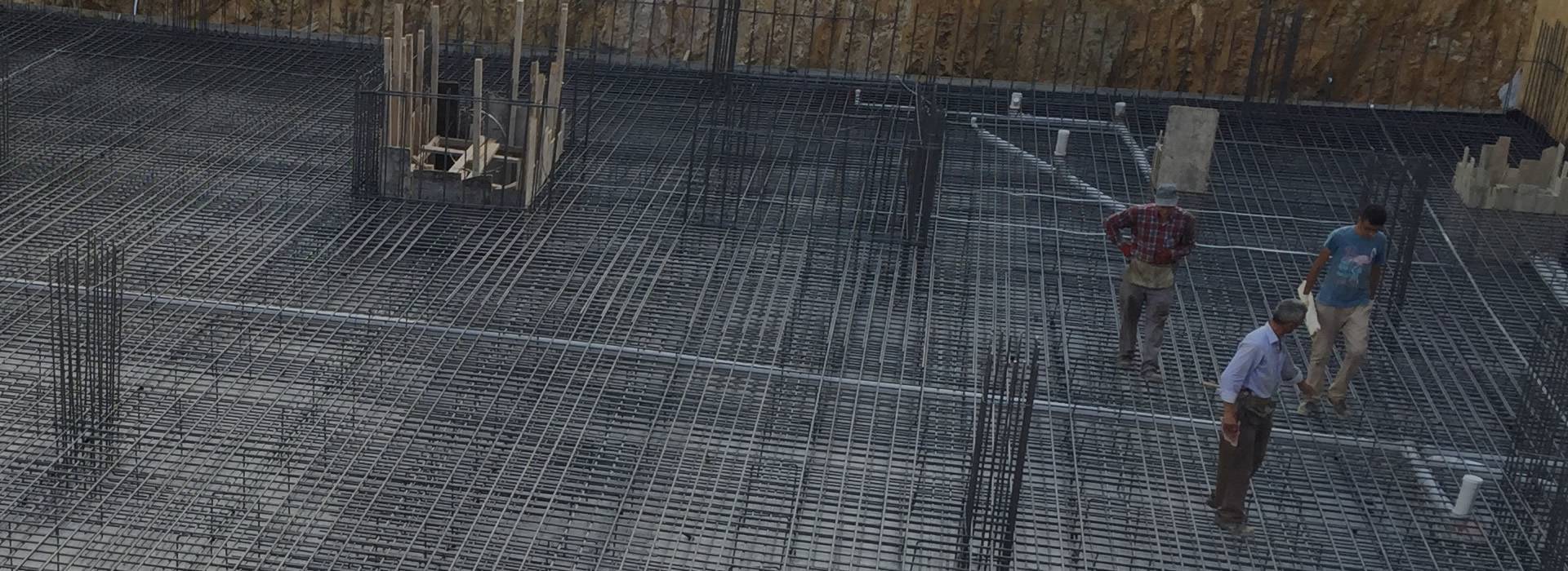 Reinforcing slab mesh used in construction structure, and two workers stand on it.